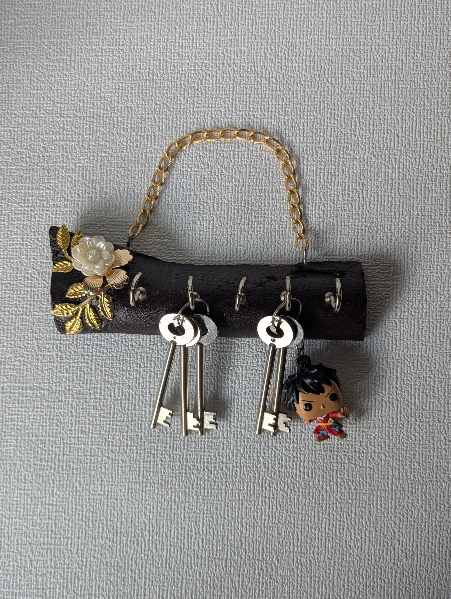 Handcrafted wooden key holder with gold floral design, metal chain, and hanging keys
