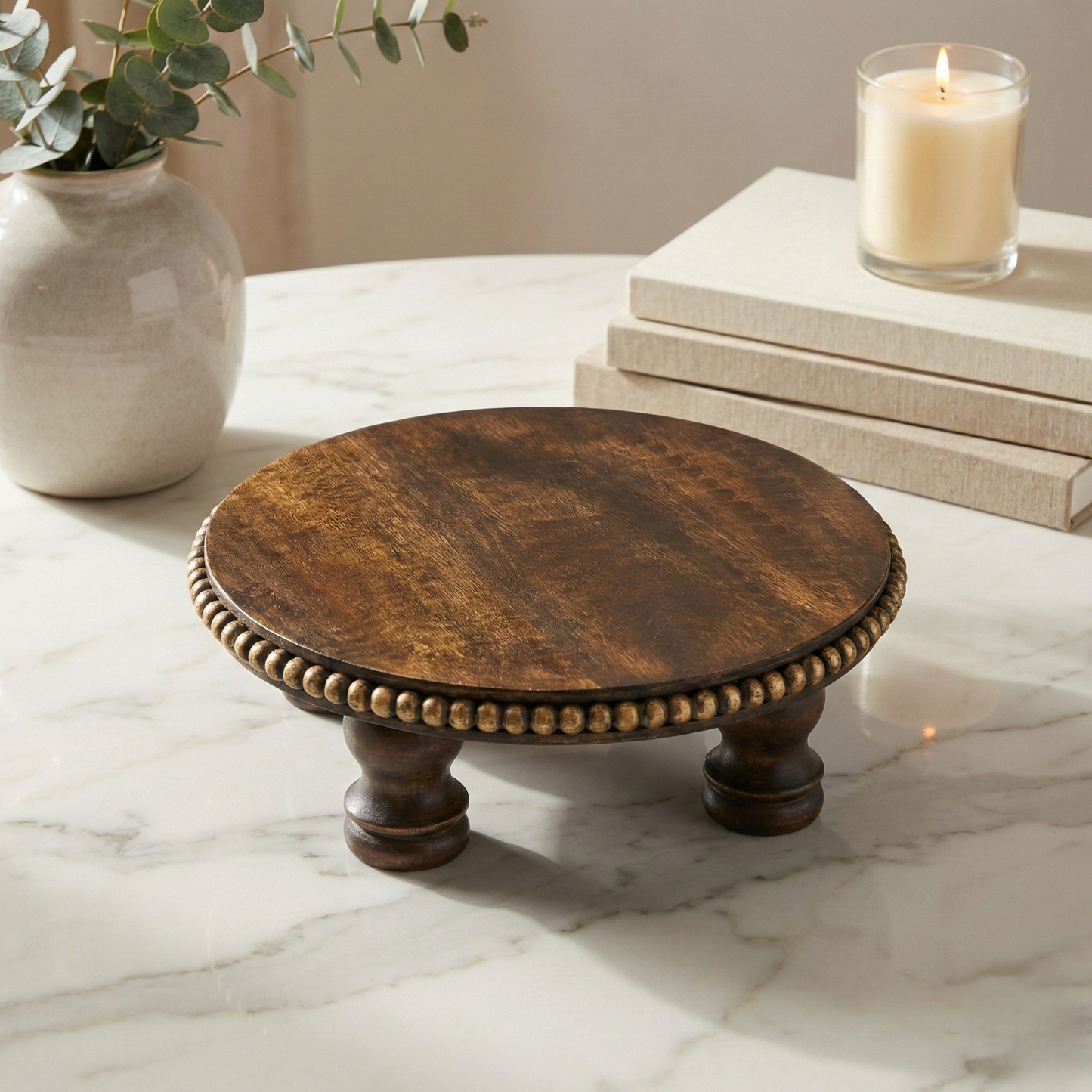 Round wooden pedestal stand with beaded edge on marble table, home decor accent.
