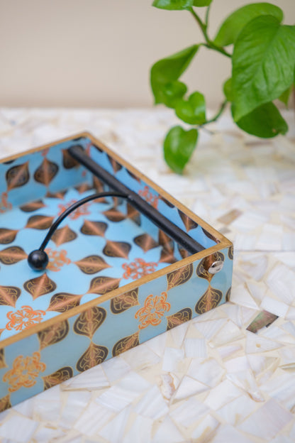 Handcrafted floral-patterned wooden tray with blue and gold design on a shell mosaic table