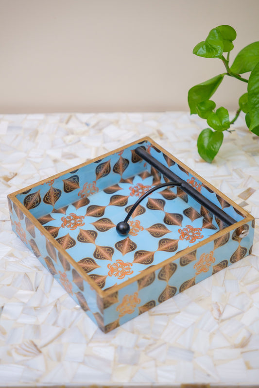 Handcrafted wooden napkin holder with blue and gold floral pattern on a mosaic surface