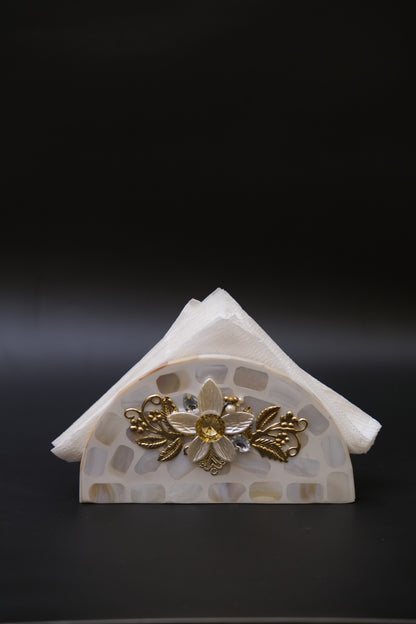 Mother of pearl napkin holder with floral and gold accents on a black background