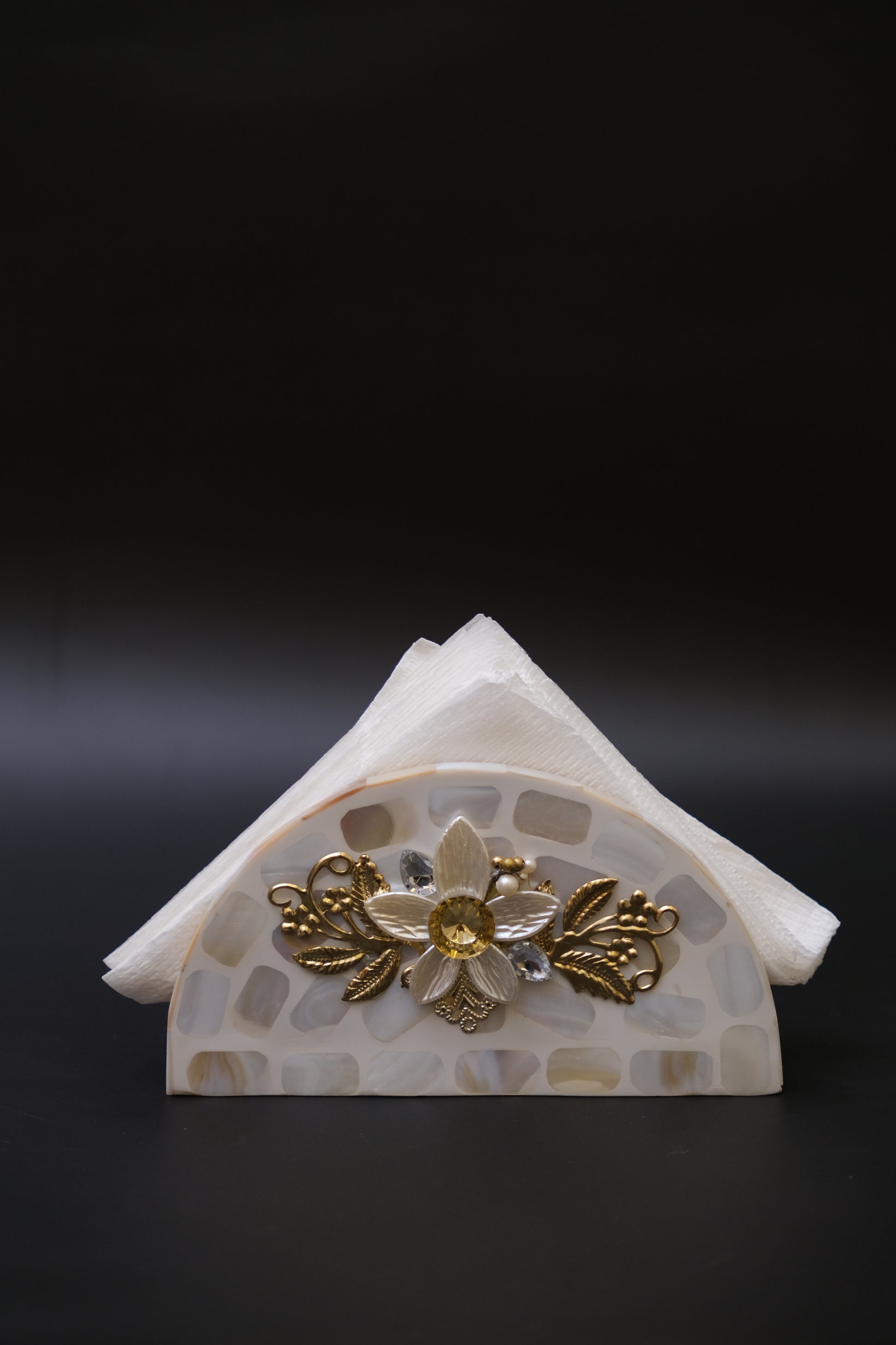 Handcrafted mother of pearl napkin holder with gold floral accents on black background