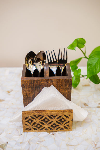 Handcrafted wooden cutlery and napkin holder with carved design on a mosaic surface