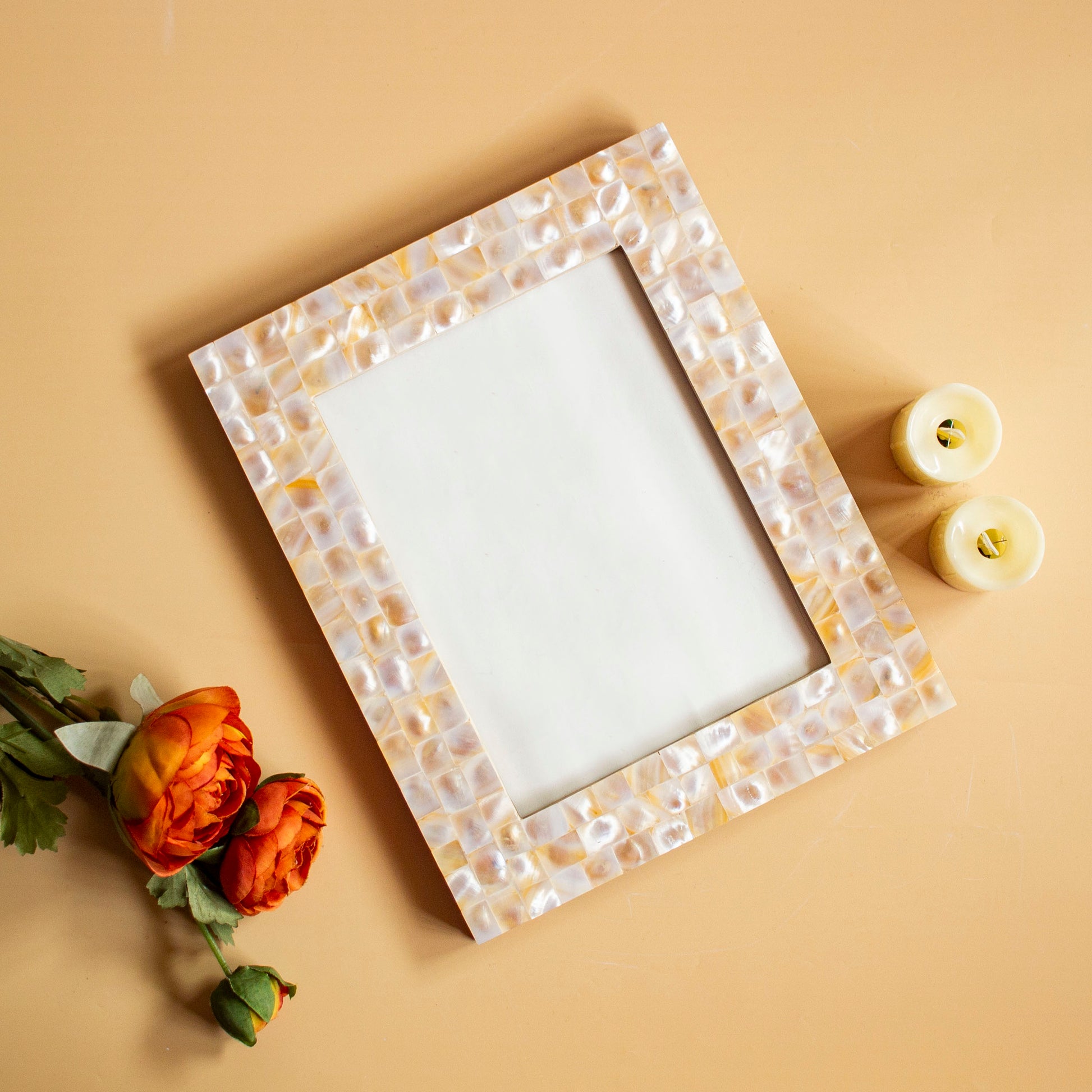 Rectangular mother of pearl photo frame with mosaic pattern, flowers, and candles on beige surface