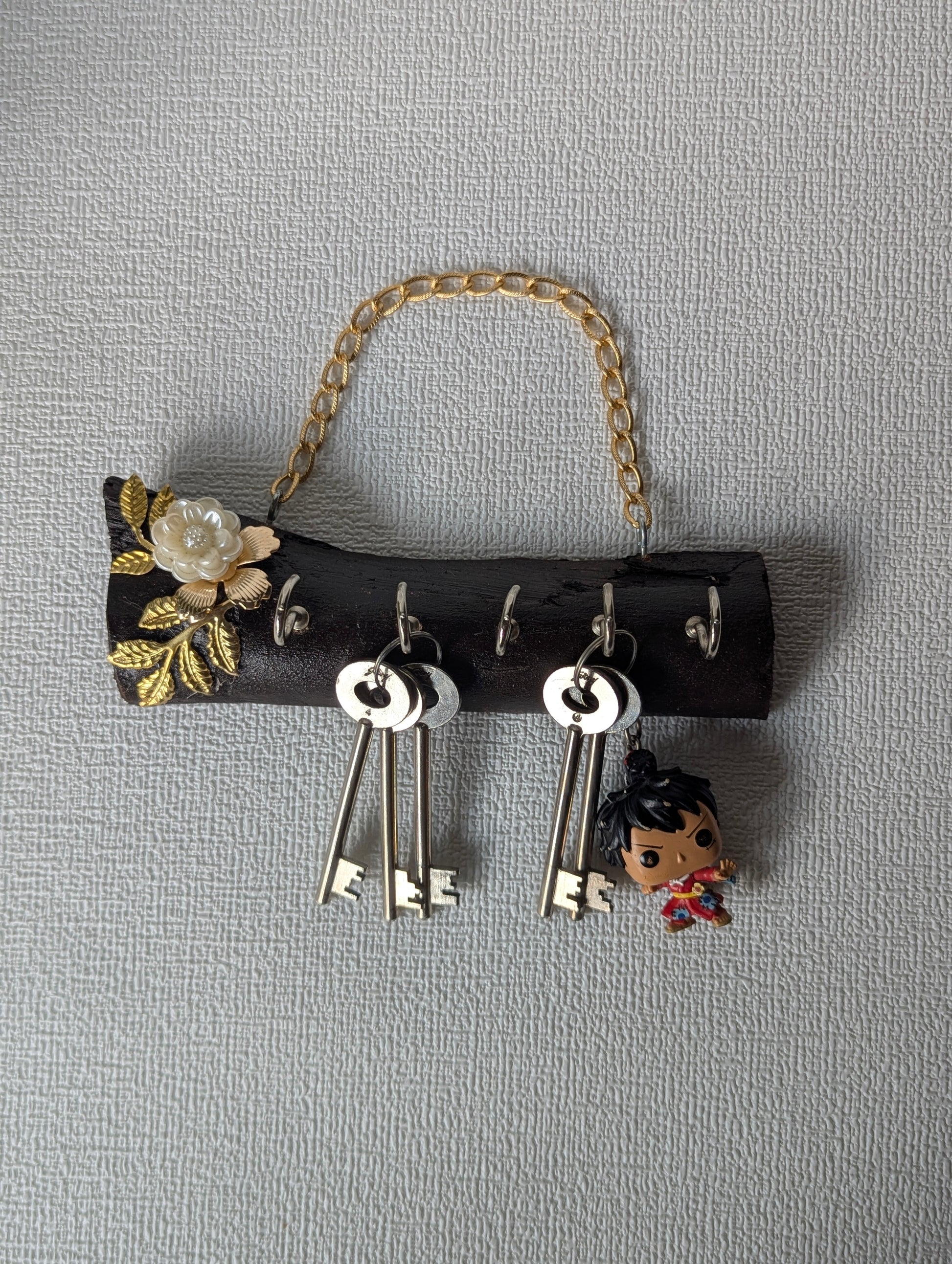 Handcrafted wooden key holder with gold floral design, metal chain, and hanging keys