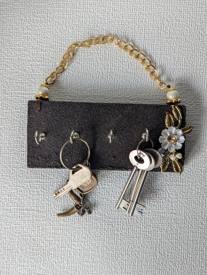 Handcrafted wooden key holder with gold chain, floral embellishments, and keys hanging