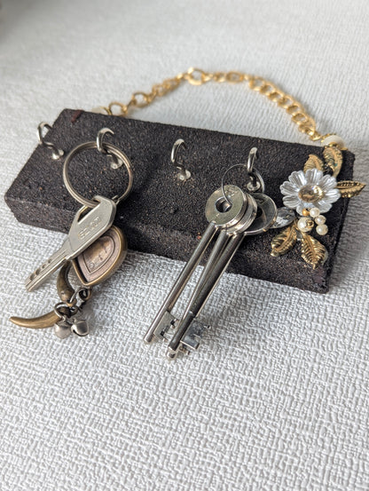 Handcrafted wooden key holder with metal hooks, floral accent, and gold chain on white surface
