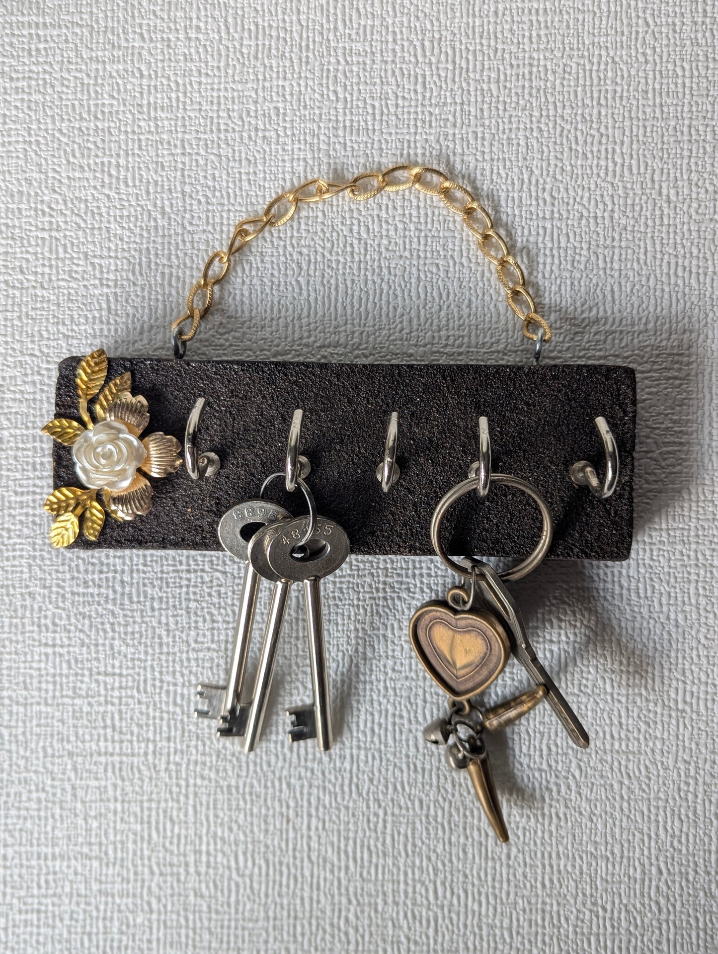 Handcrafted key holder with gold chain, floral embellishment, and hanging keys