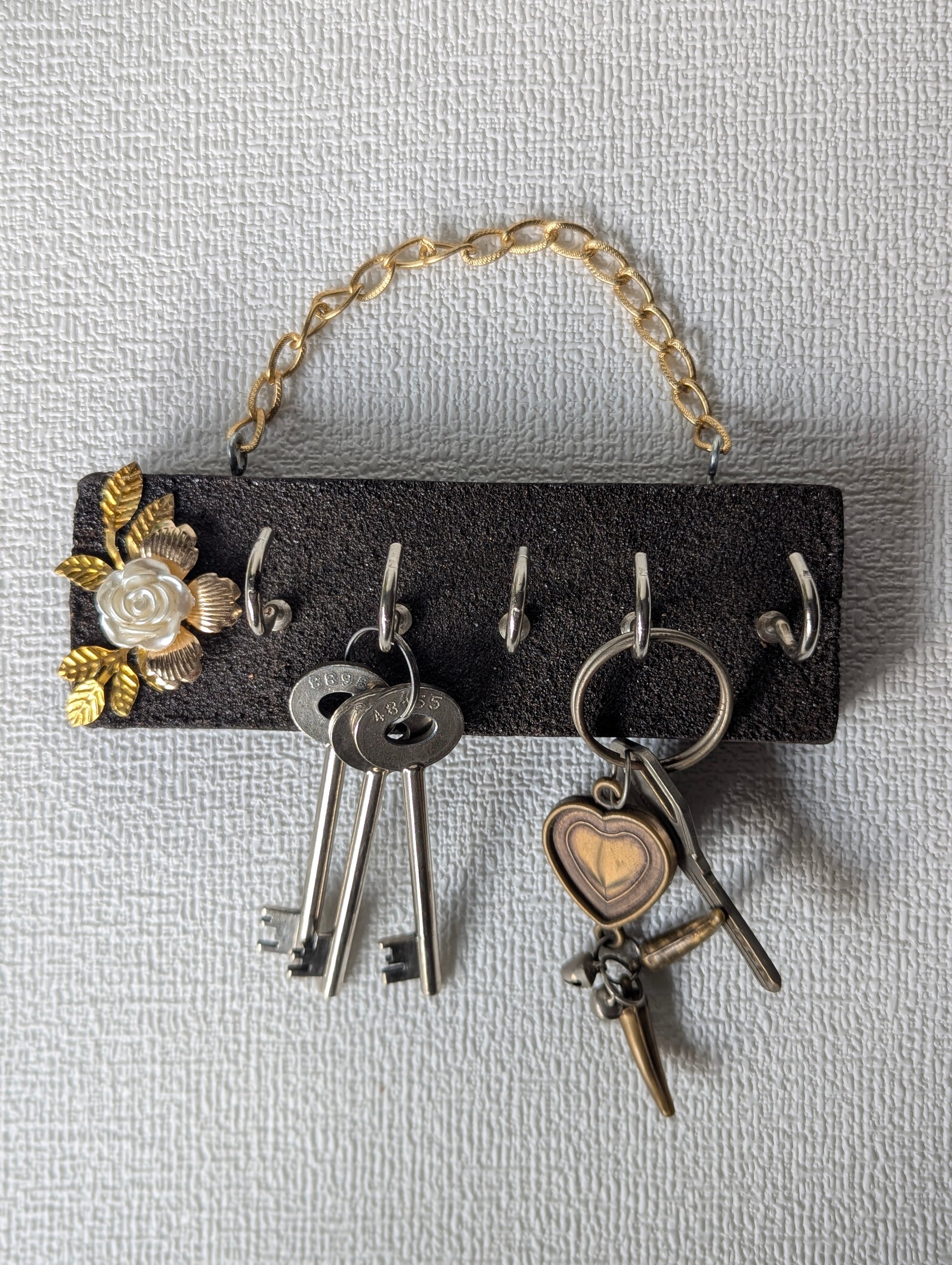 Handcrafted key holder with gold chain, floral embellishment, and hanging keys
