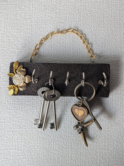 Handcrafted key holder with gold chain, floral embellishment, and hanging keys