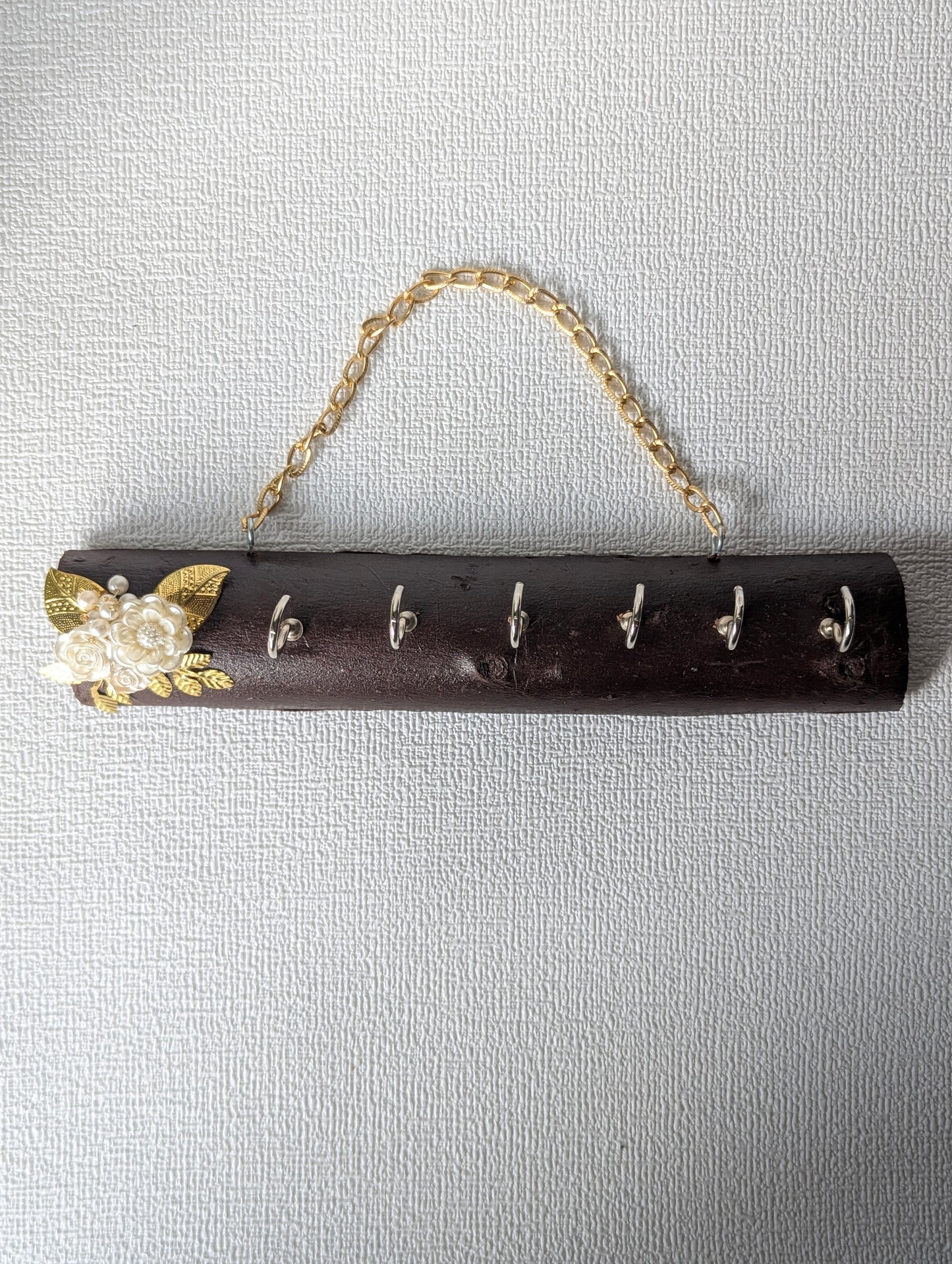 Handcrafted wooden key holder with floral embellishment and gold chain, wall mounted decor