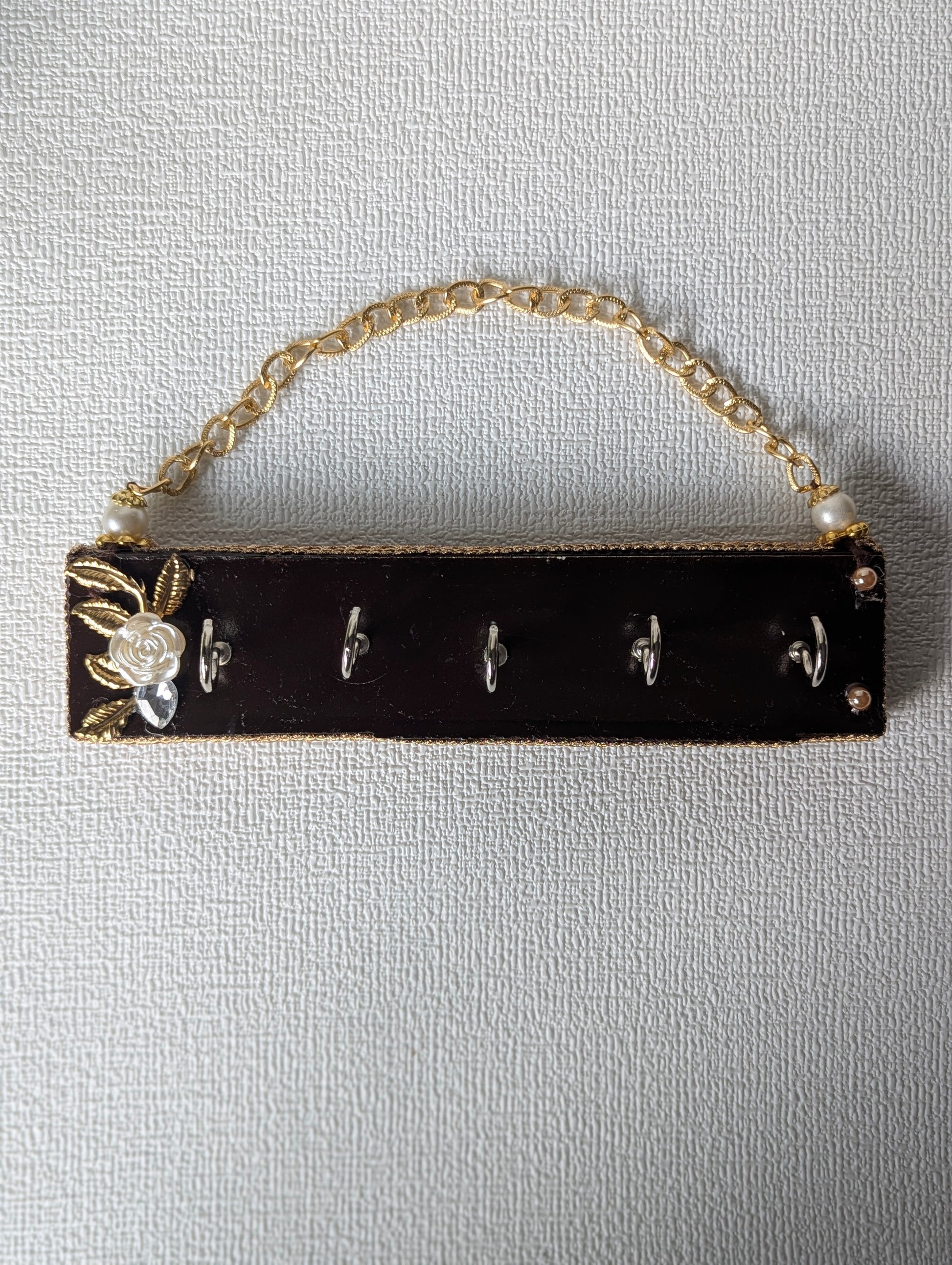 Handcrafted wooden key holder with gold chain, floral accent, and five metal hooks