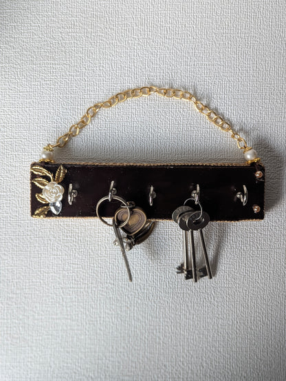 Handcrafted wooden key holder with floral inlay, gold chain, and multiple keys hanging