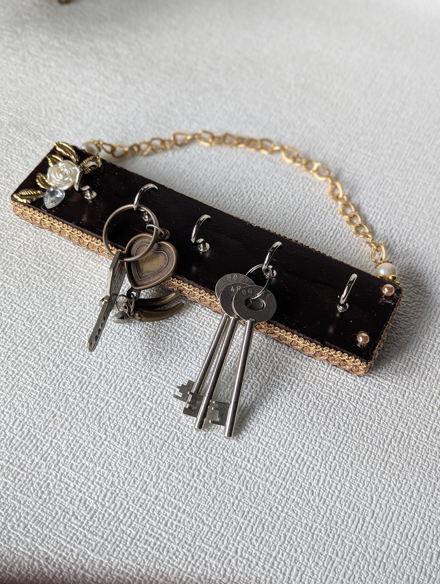 Handcrafted wooden key holder with floral embellishment and attached metal keys