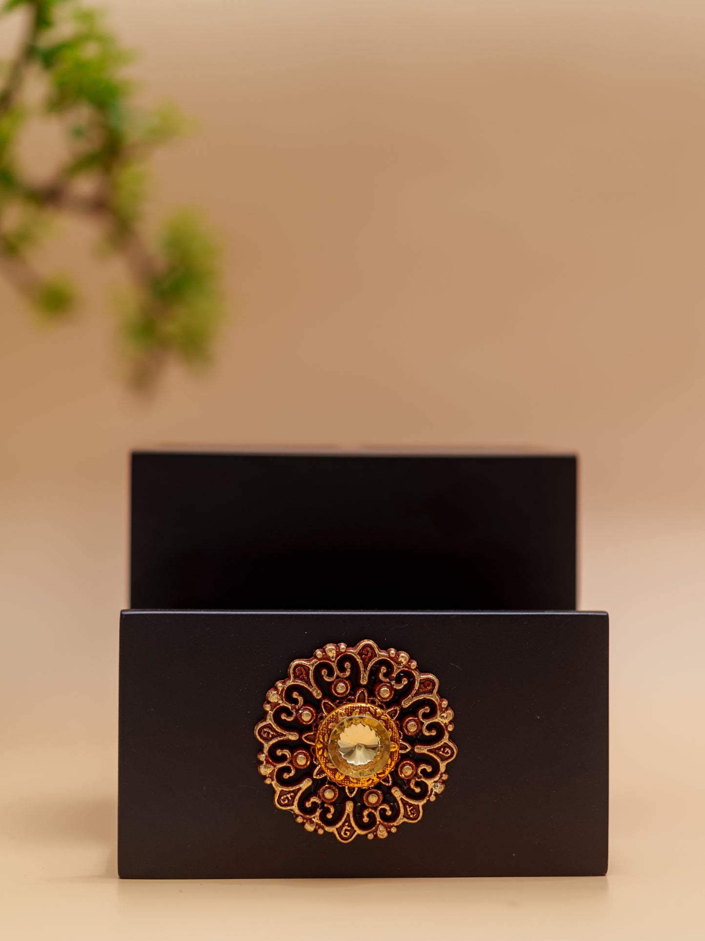 Intricately designed golden floral decorative knob on black wooden drawer