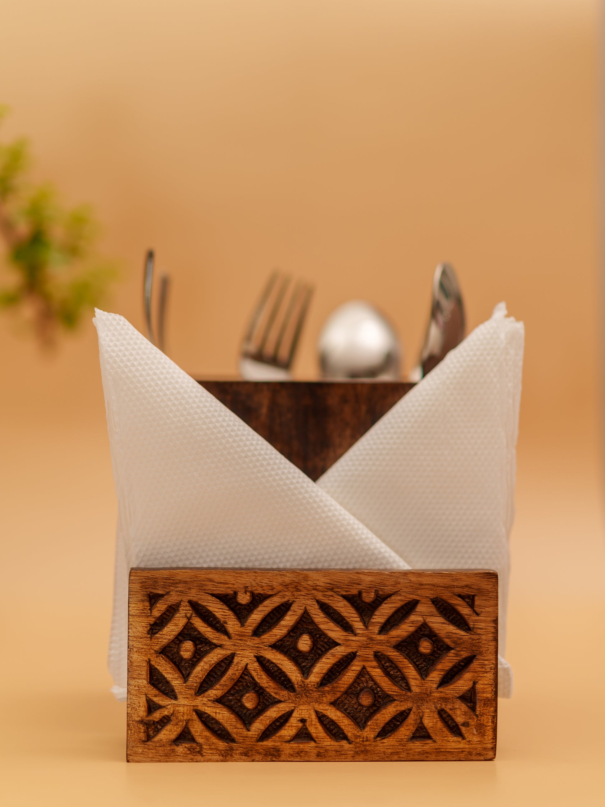 Handcrafted wooden napkin holder with intricate floral carving, holding cutlery and napkins.