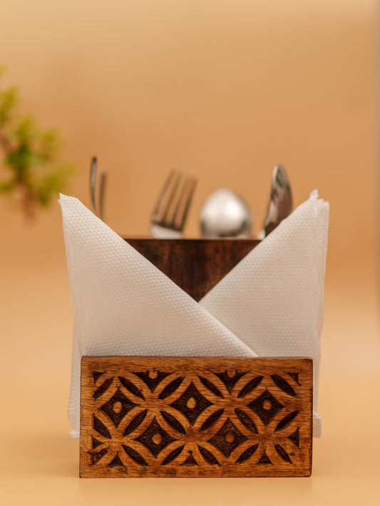 Handcrafted wooden napkin holder with intricate floral carving, holding cutlery and napkins.
