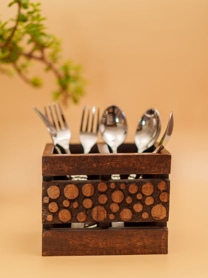 Handcrafted wooden cutlery holder with textured circles, filled with silverware on beige background