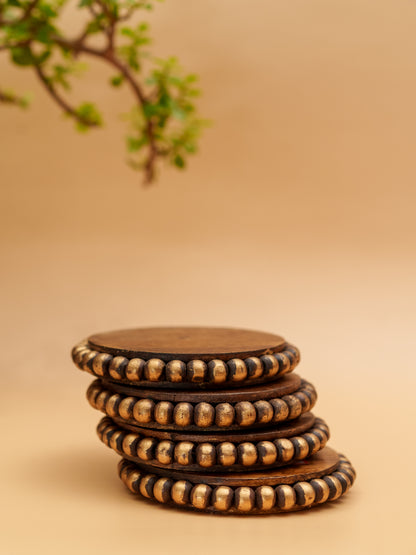 Stack of handcrafted wooden coasters with gold beaded edges on beige background