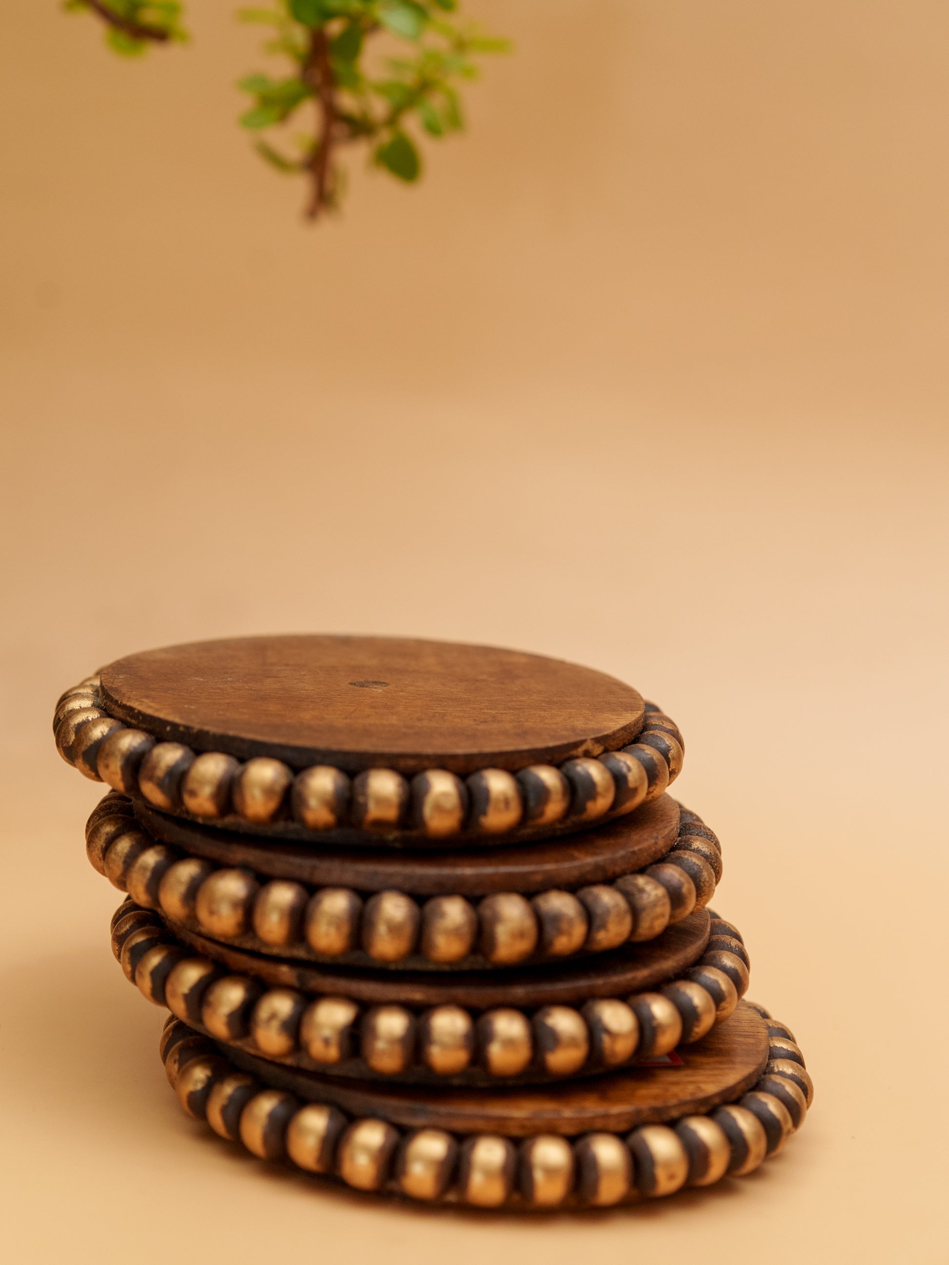 Stack of handcrafted wooden coasters with decorative gold beaded edges
