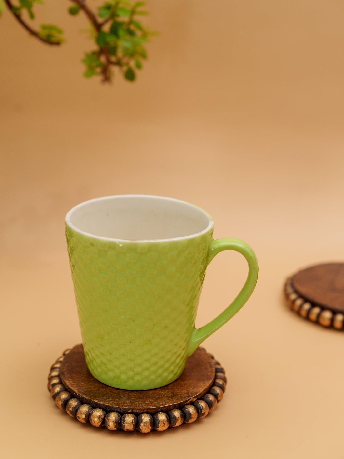 Green textured ceramic mug on wooden beaded coaster, minimal earthy background
