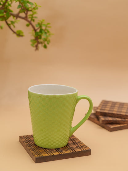 Green textured ceramic mug on wooden coaster with plaid pattern, minimal decor background