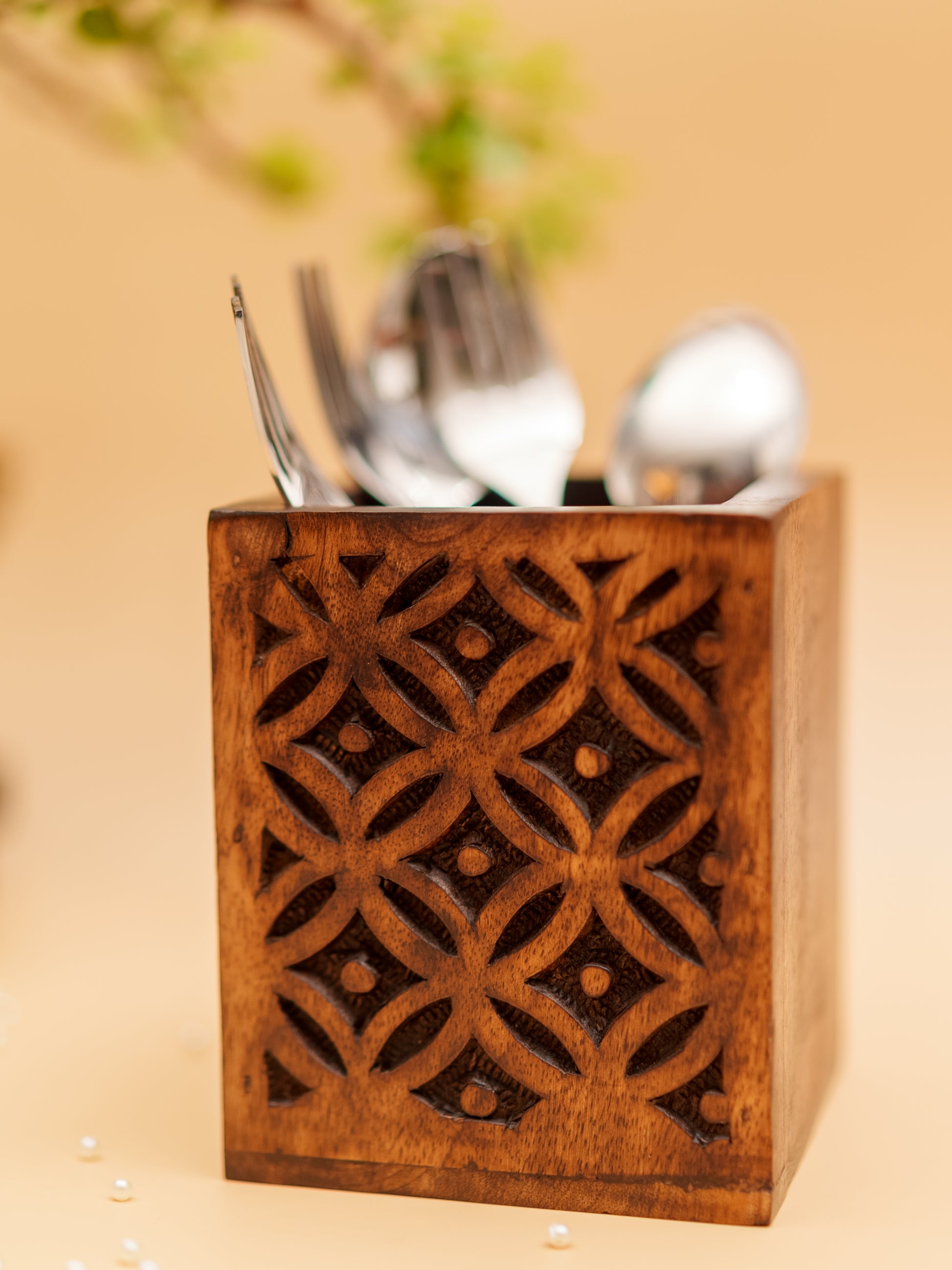 Handcrafted wooden cutlery holder with geometric floral carving, holding silver utensils